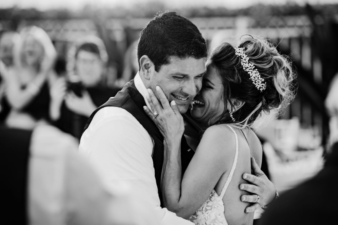 Intimate beach wedding with a bride and groom hugging during their first dance.