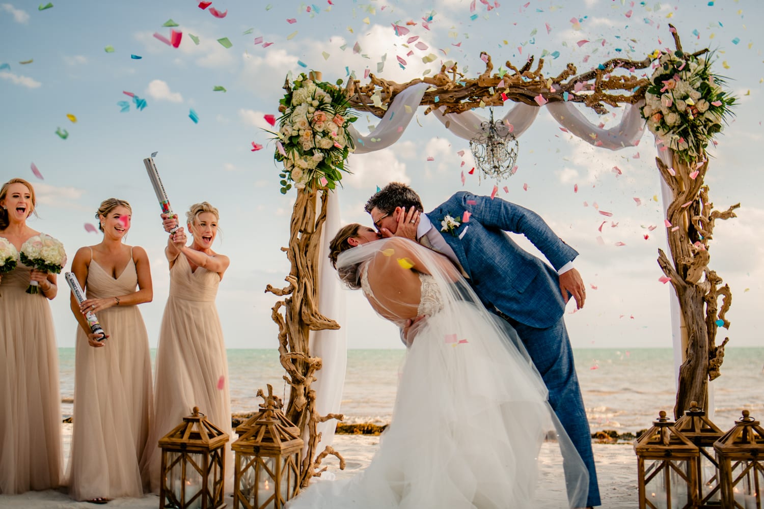 A bride and groom kiss under a confetti arch at Casa Marina wedding.