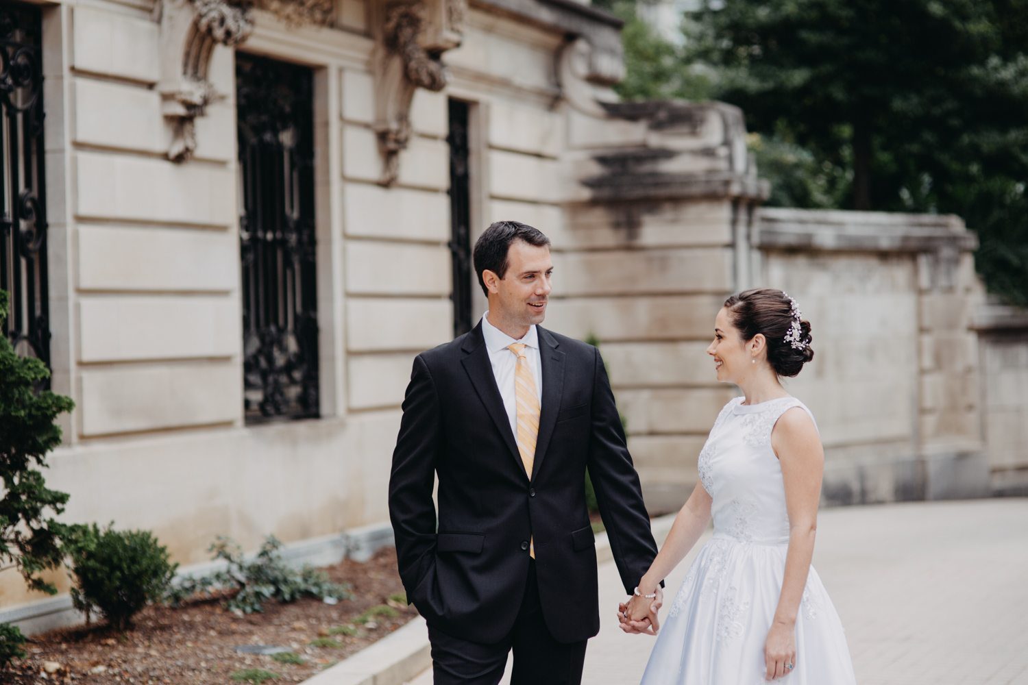 A bride and groom holding hands in front of the Cosmos Club in Washington DC for their Dupont Circle wedding.