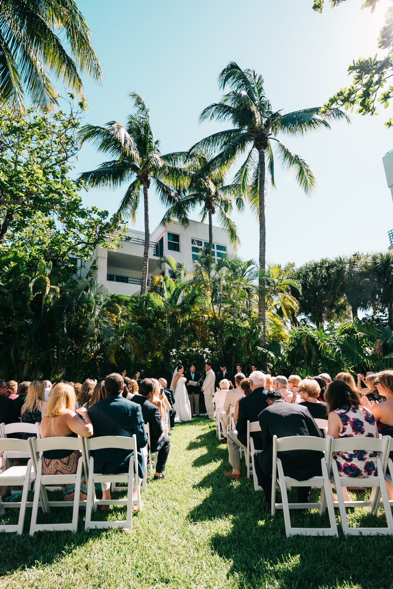 A picturesque outdoor wedding ceremony with palm trees in the background, reminiscent of Truman White House weddings held in Key West.