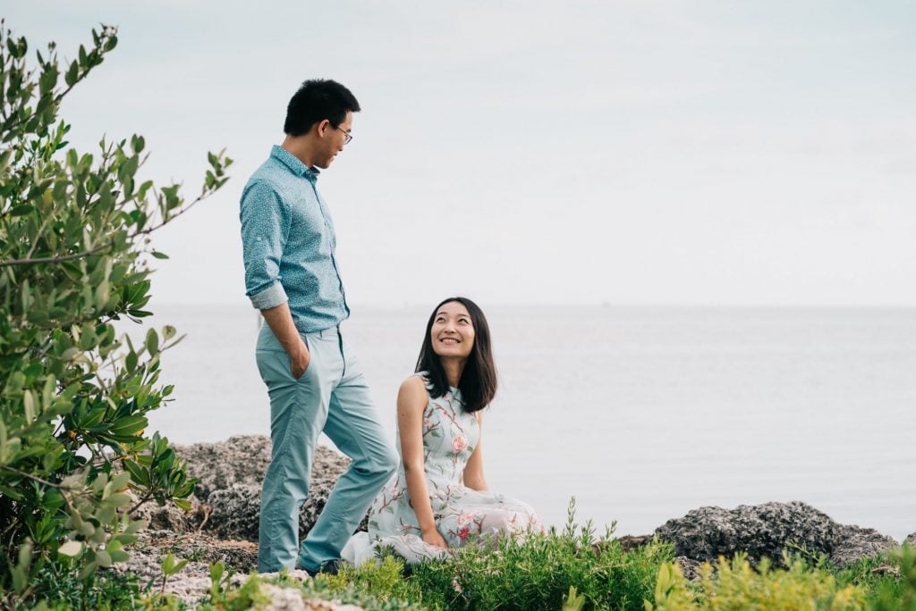 Xiao and Ying enjoying a sunset engagement session on rocks near the water in Key West, FL.