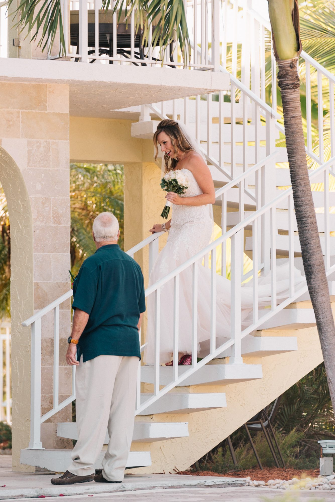 A bride walks down the stairs at her Destination Wedding in the Florida Keys to her father.