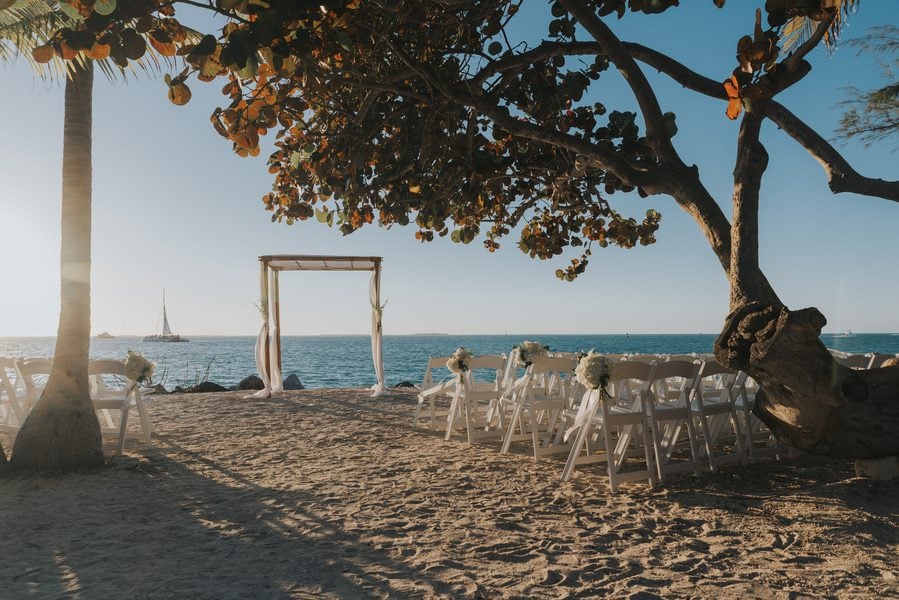 A Key West beach wedding at Fort Zachary Taylor with chairs and trees on the sand.
