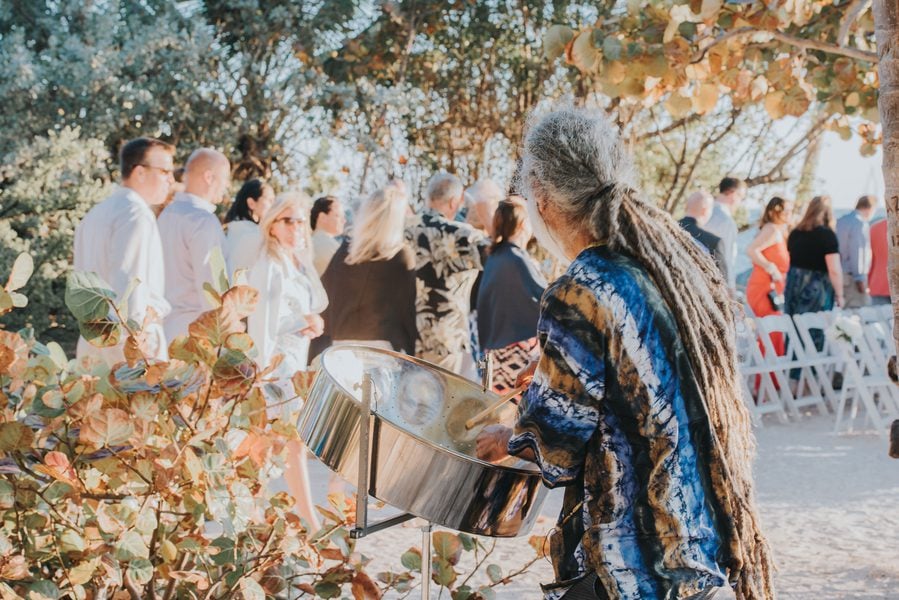 A woman with dreadlocks holding a steel drum at a Fort Zachary Taylor outdoor wedding.