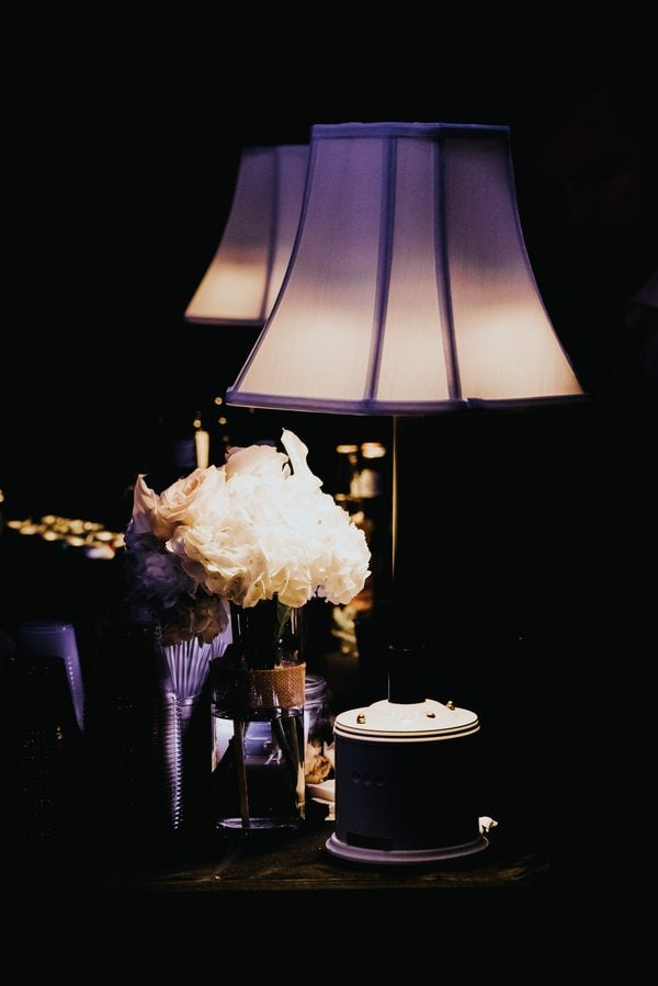 A Key West wedding photographer captures a lamp on a table next to a vase of flowers at a Fort Zachary Taylor wedding.