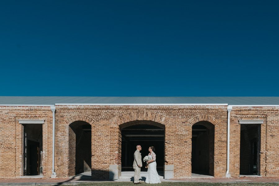 A Key West bride and groom standing in front of a fort building.