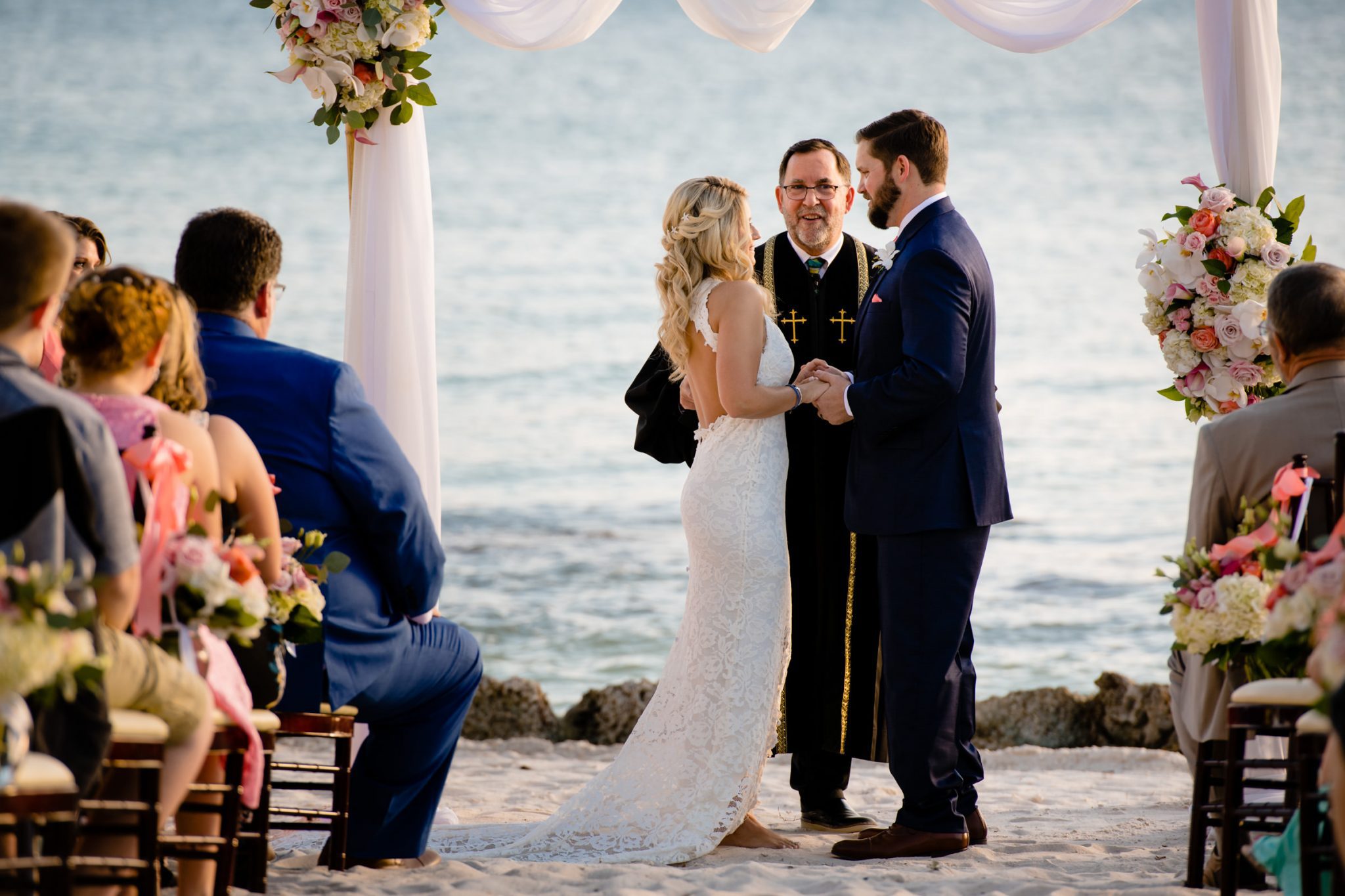 A bride and groom exchange vows on the beach.
