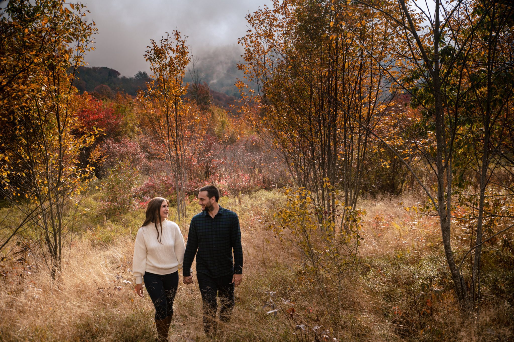 couple walking in fall colors at graveyard fields during asheville engagement session