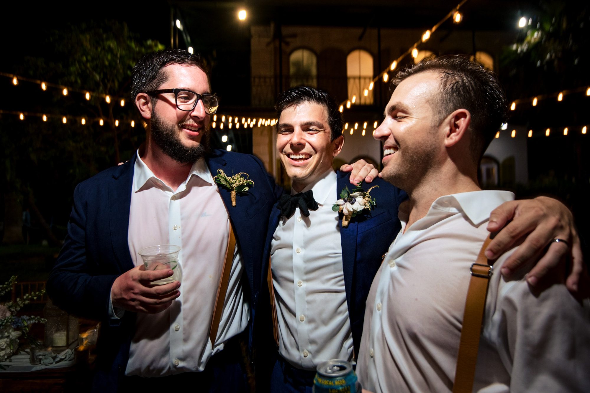Three groomsmen smiling at each other at a Hemingway House wedding.
