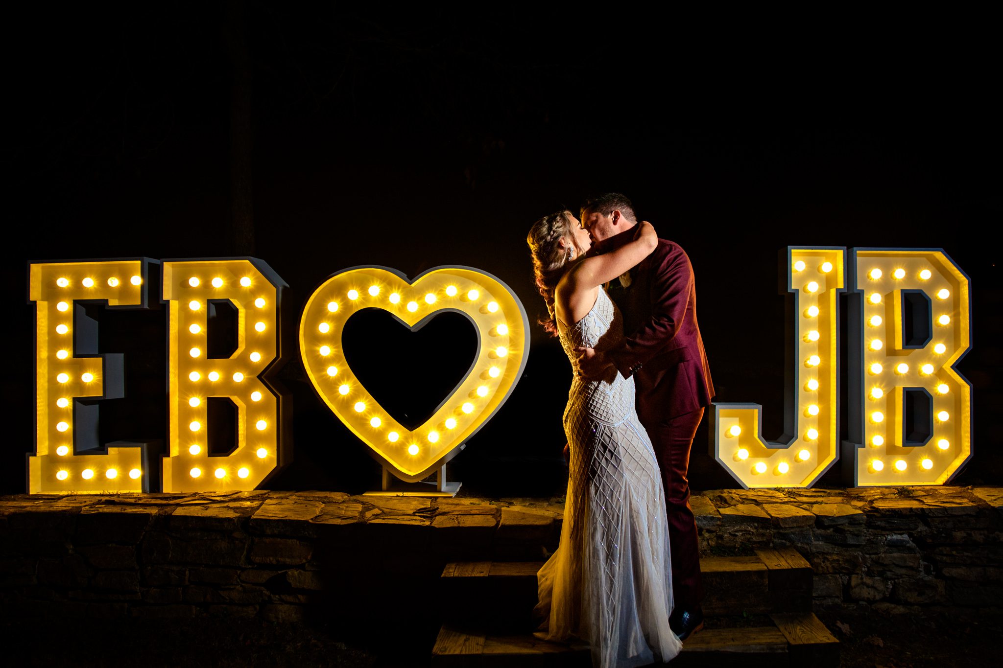 bride and groom in front of lightup neon sign