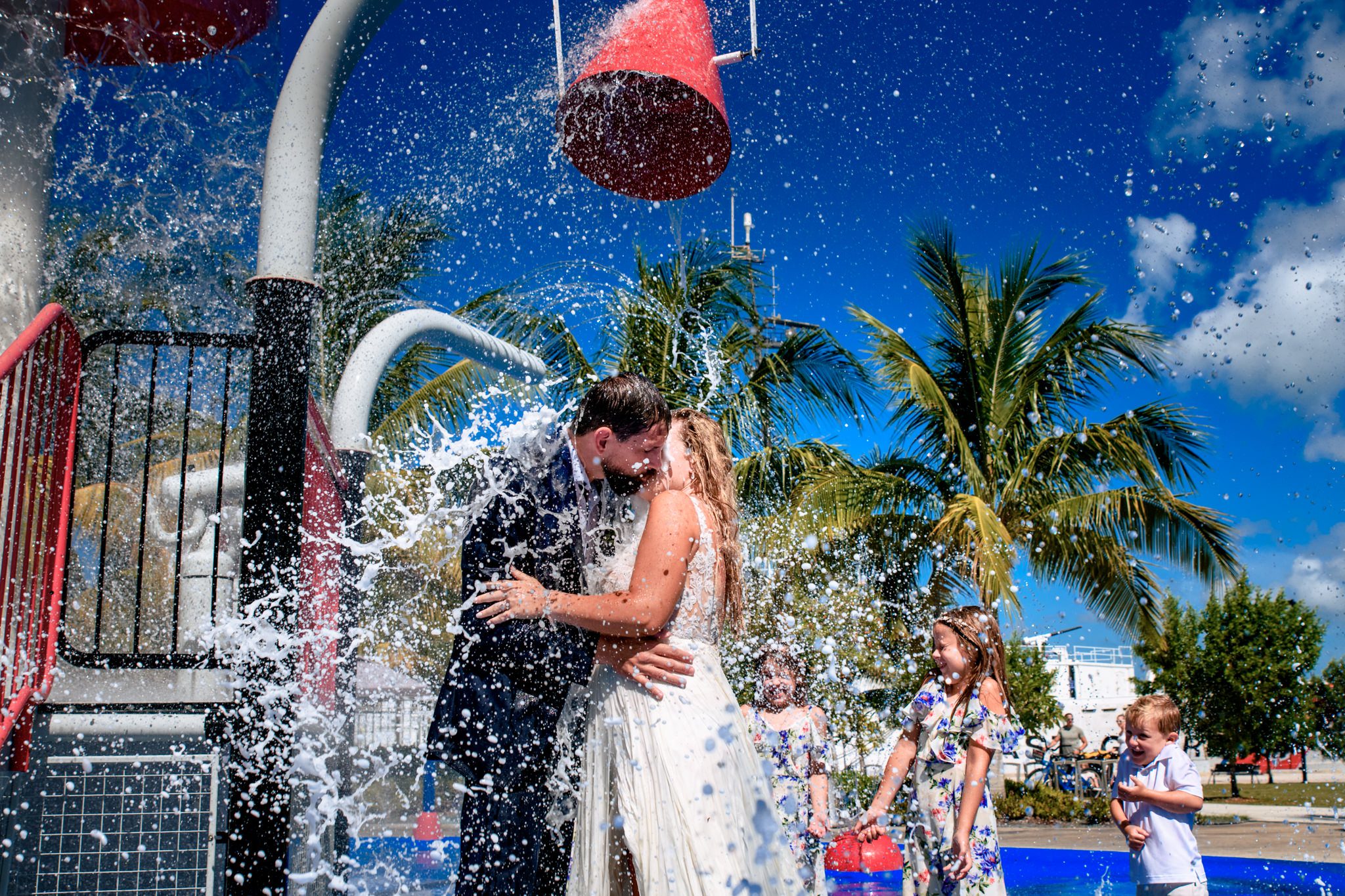 bride and groom kissing at splash park under water during trash the dress session