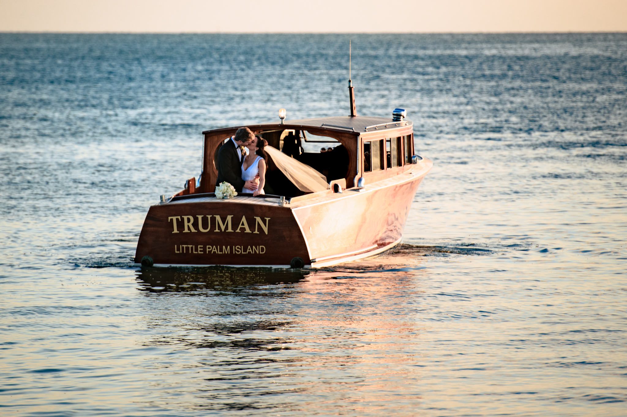 bride and groom kissing on the back of truman boat at little palm island