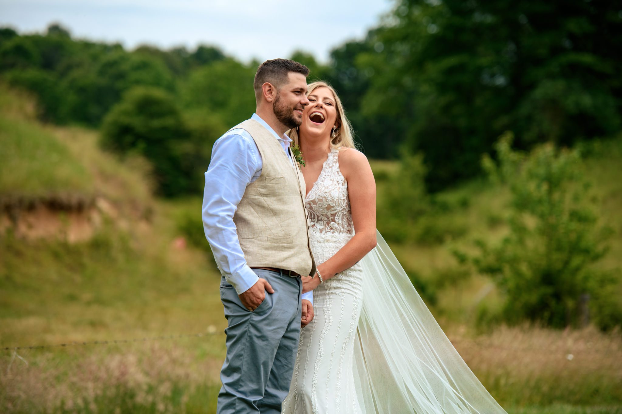 Bride and groom laughing while embracing in the pasture at Barnstar events in Waynesville North Carolina shot while being a second photographer