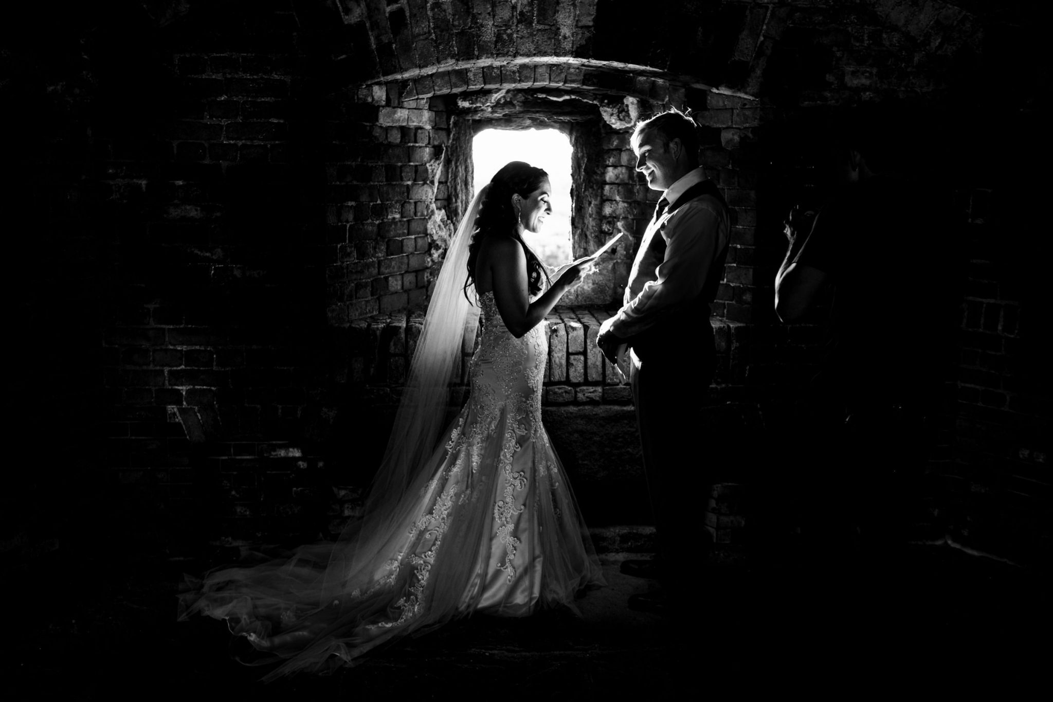 backlit photo of bride reading her vows to her groom inside of fort zachary taylor in key west florida
