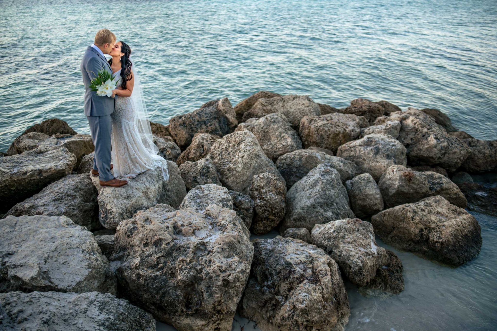Bride and groom portraits on top of rocks during sunrise on Smathers Beach in Key West Florida