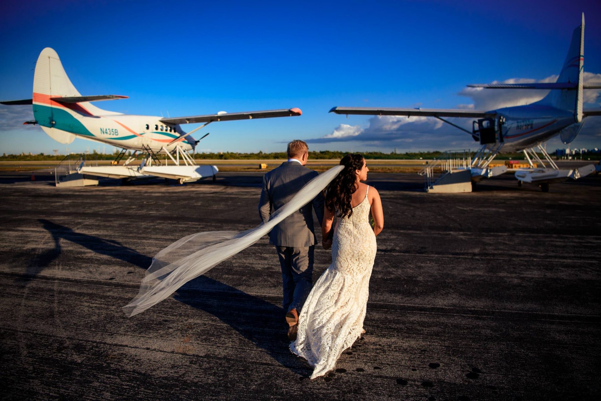 Florida Keys wedding photographer captures bride and groom walking past small planes.