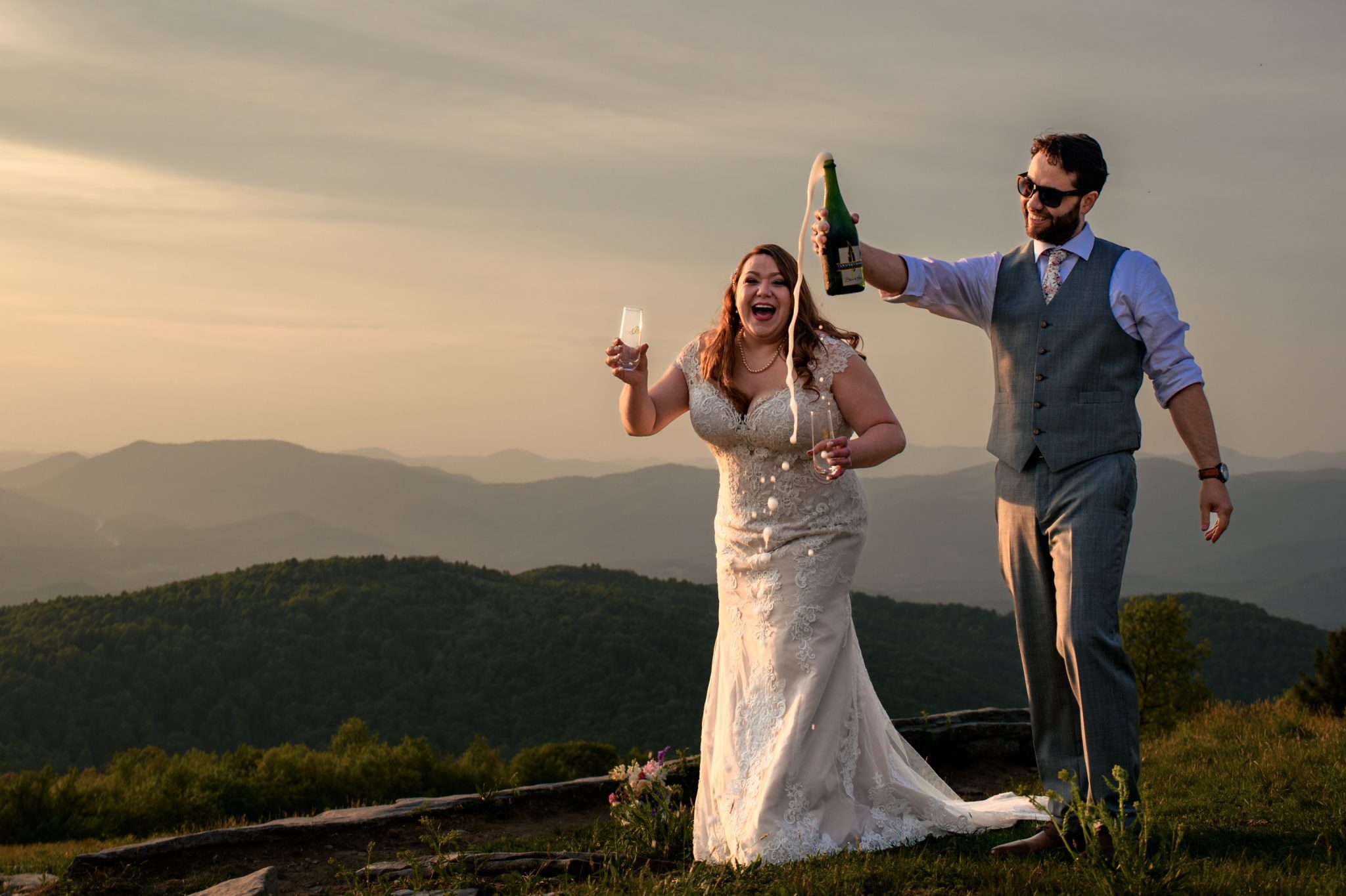 Bride and groom popping champagne on top of a mountain top