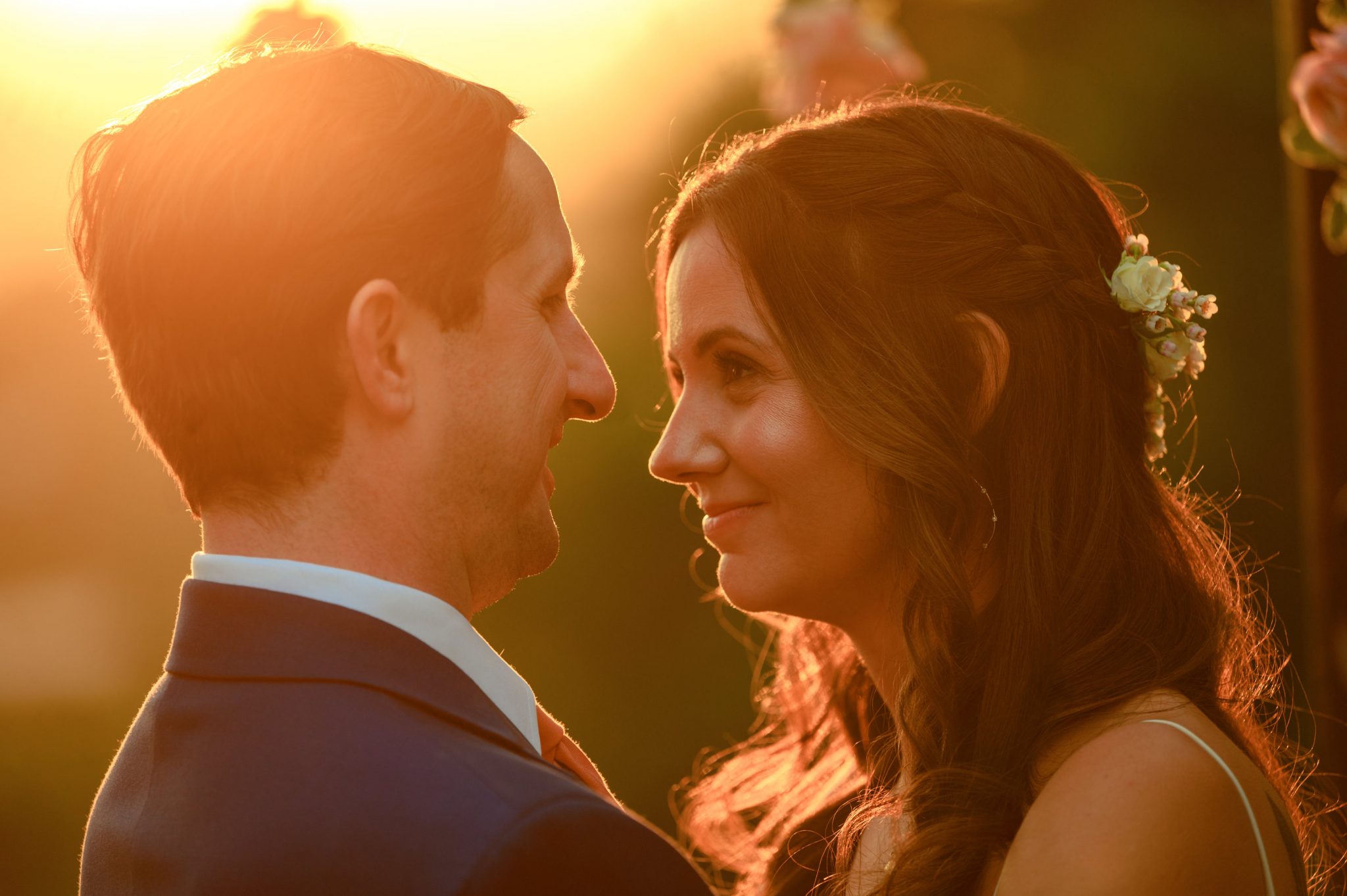 backlit photo of bride and groom at sunset during golden hour red glow