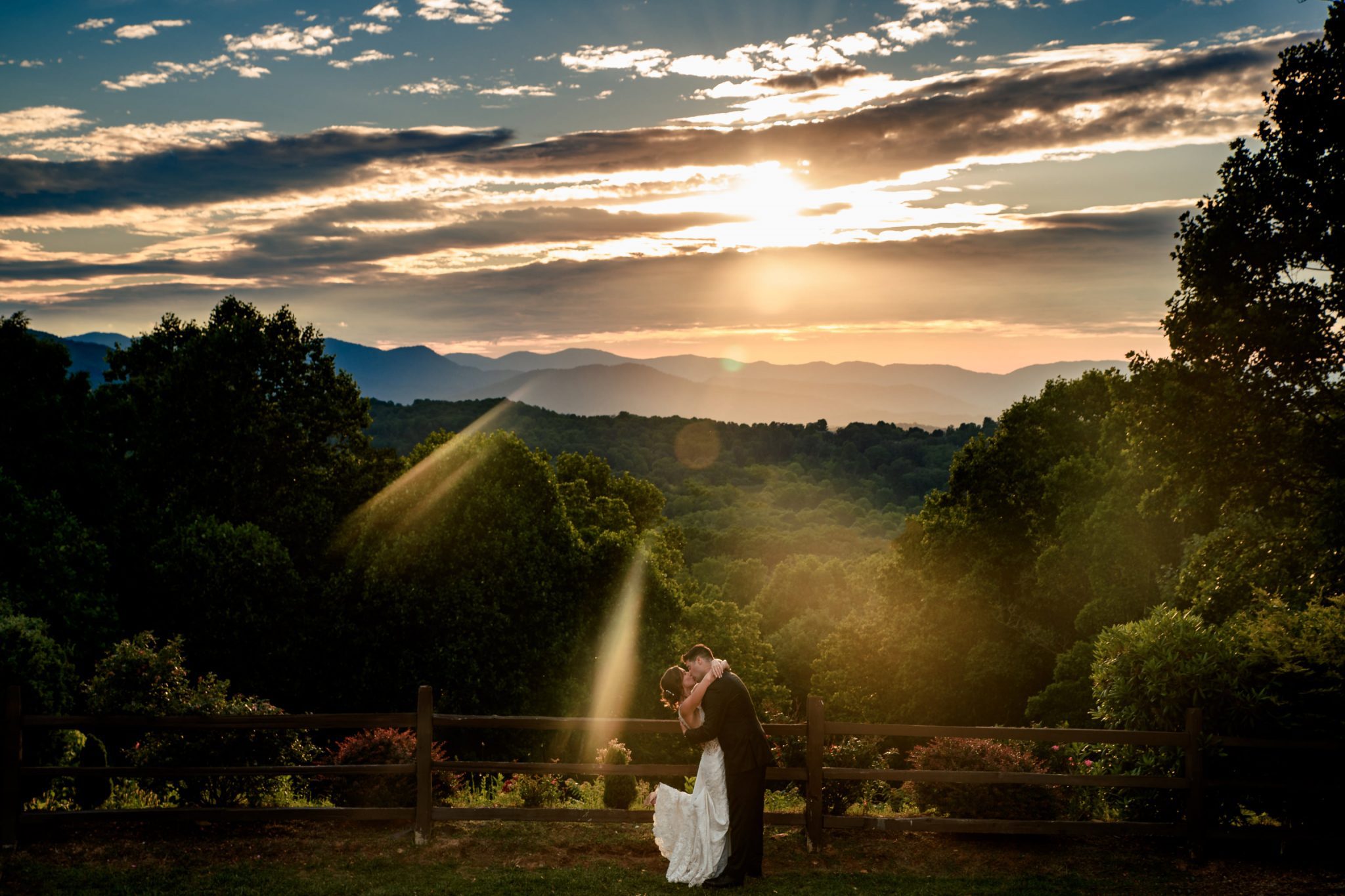 bride and groom kissing with bride kicking up foot at sunset