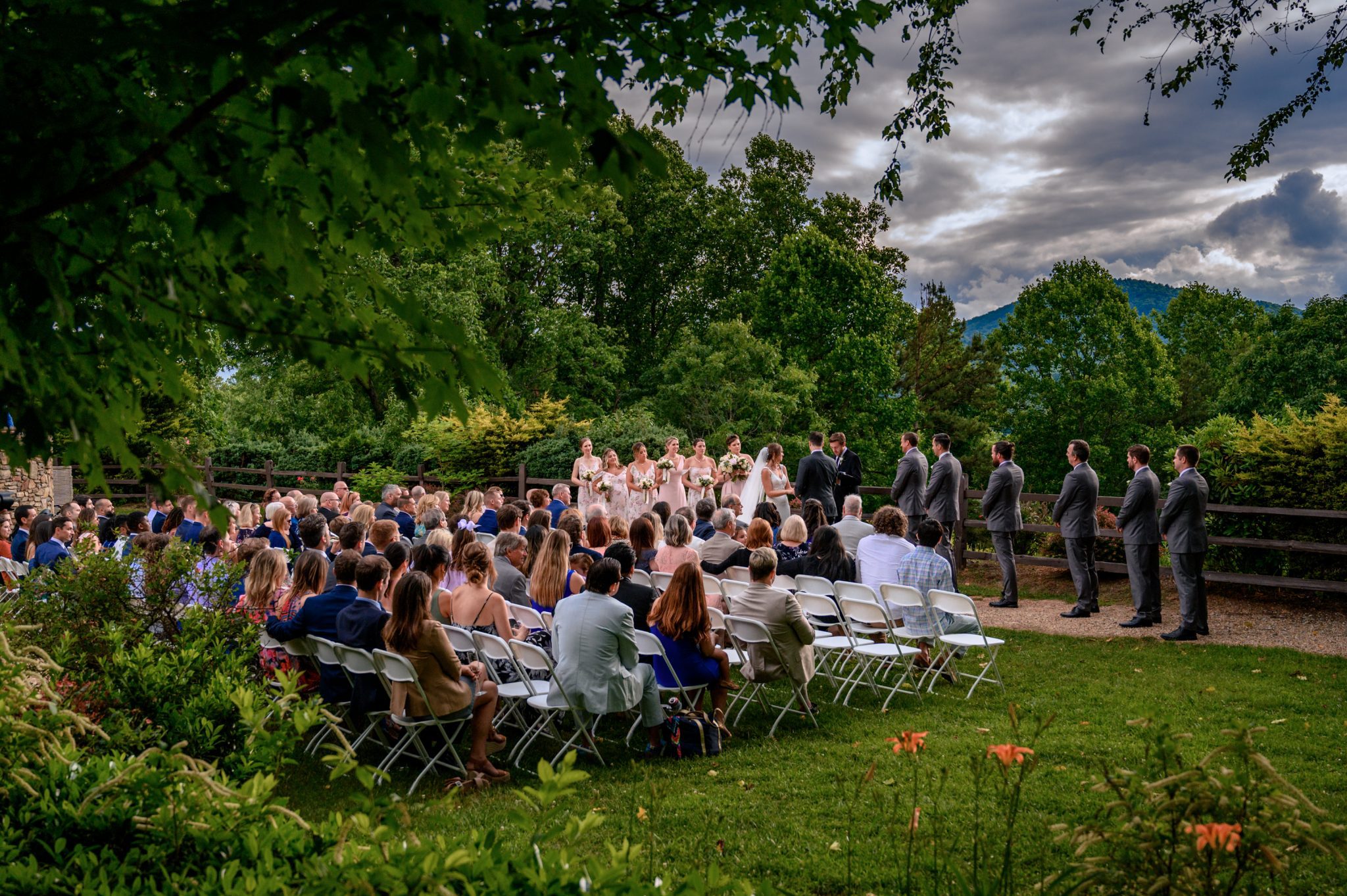 150 wedding guests sitting in white chairs during wedding ceremony on crest pavilion lawn