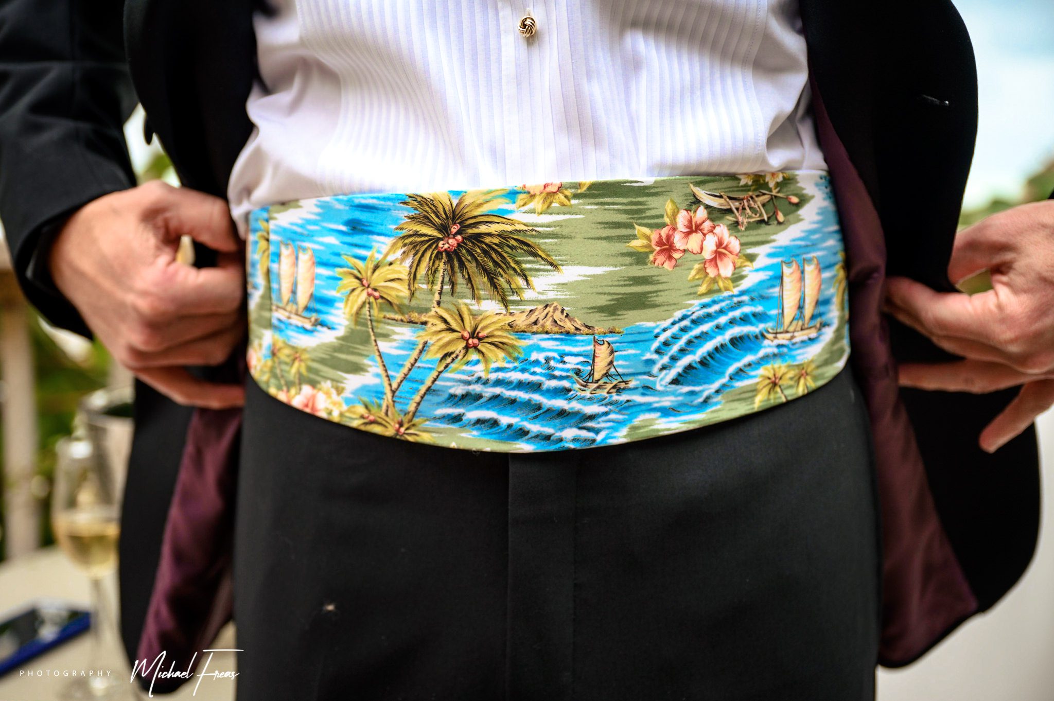 A man in a tuxedo is wearing a belt with a Florida Keys theme.