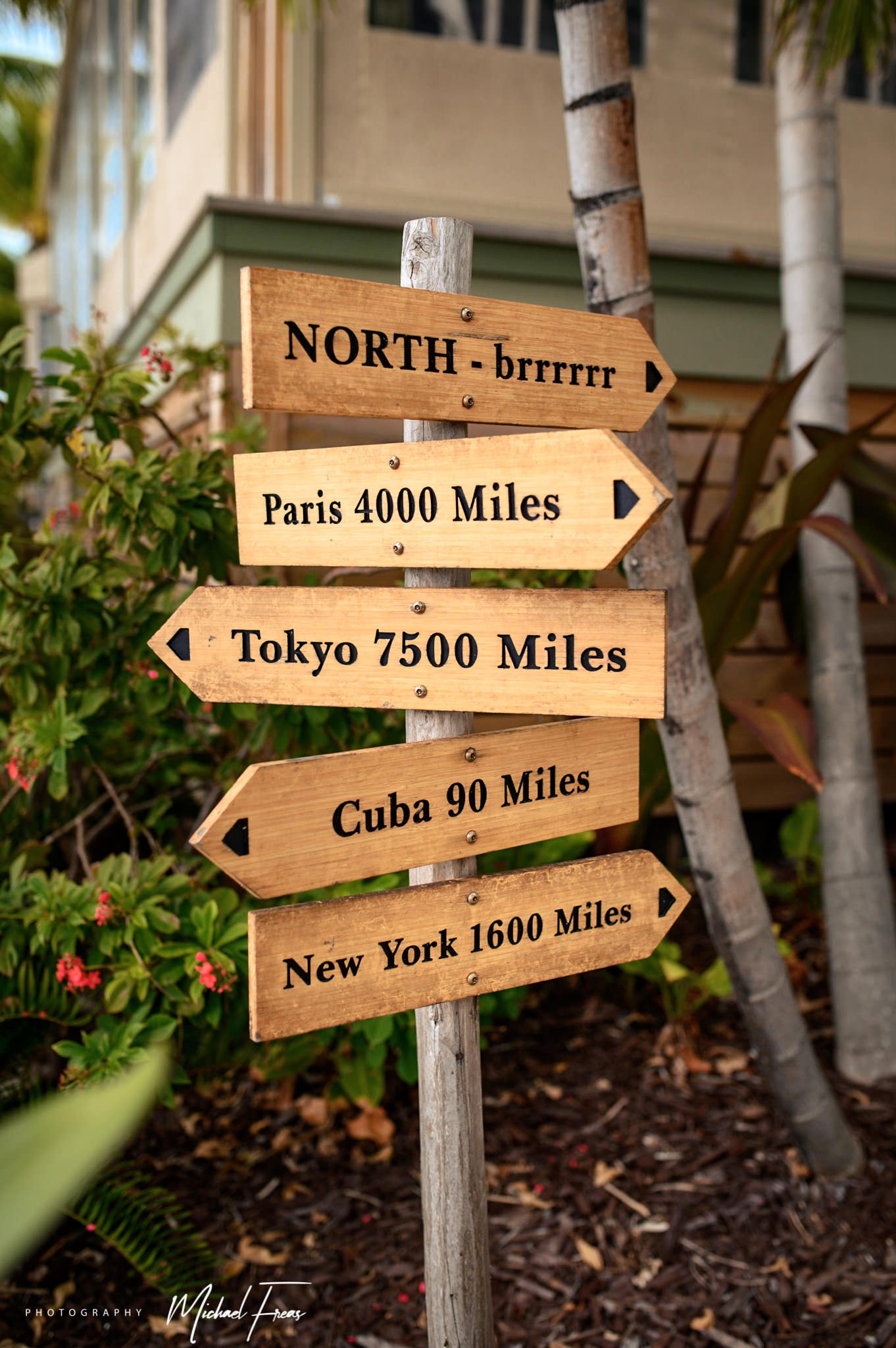 A wooden sign with arrows pointing in different directions, indicating Florida Keys destination.