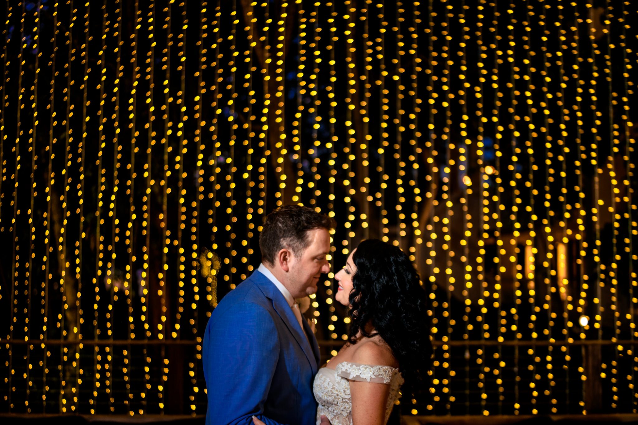 bride and groom posing for photos in front of twinkle light wall bakers cay resort wedding