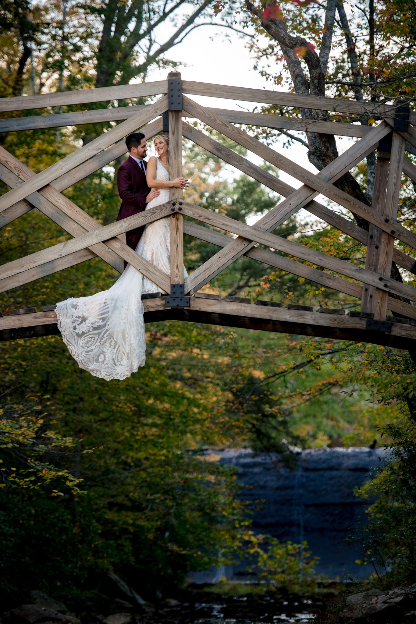 Bride and groom kissing while standing on a rock in the stream at Prince William Forest Park with fall colors in the background