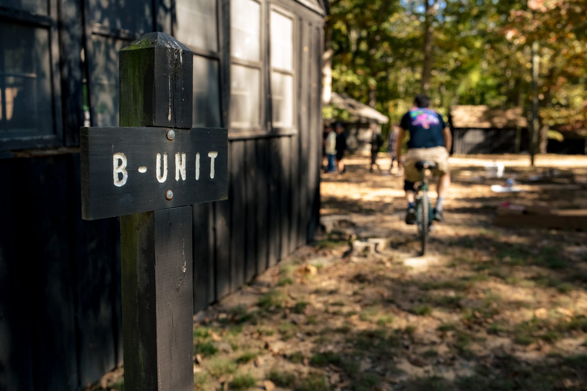 Wedding guest riding bicycle past cabin at Prince William Forest Park