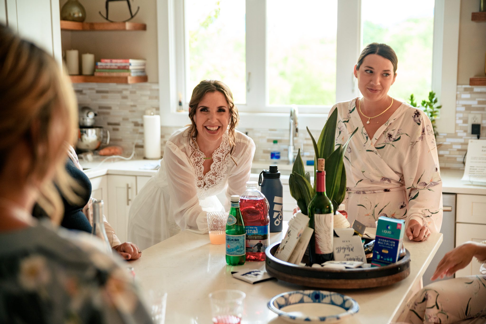 A group of women at Crest Pavilion, gathered around a kitchen counter, captured by a documentary wedding photographer.