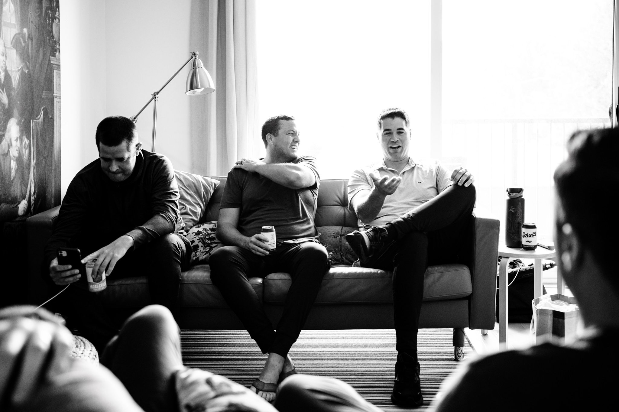 A documentary wedding photographer captures a group of men sitting on a couch at Crest Pavilion.