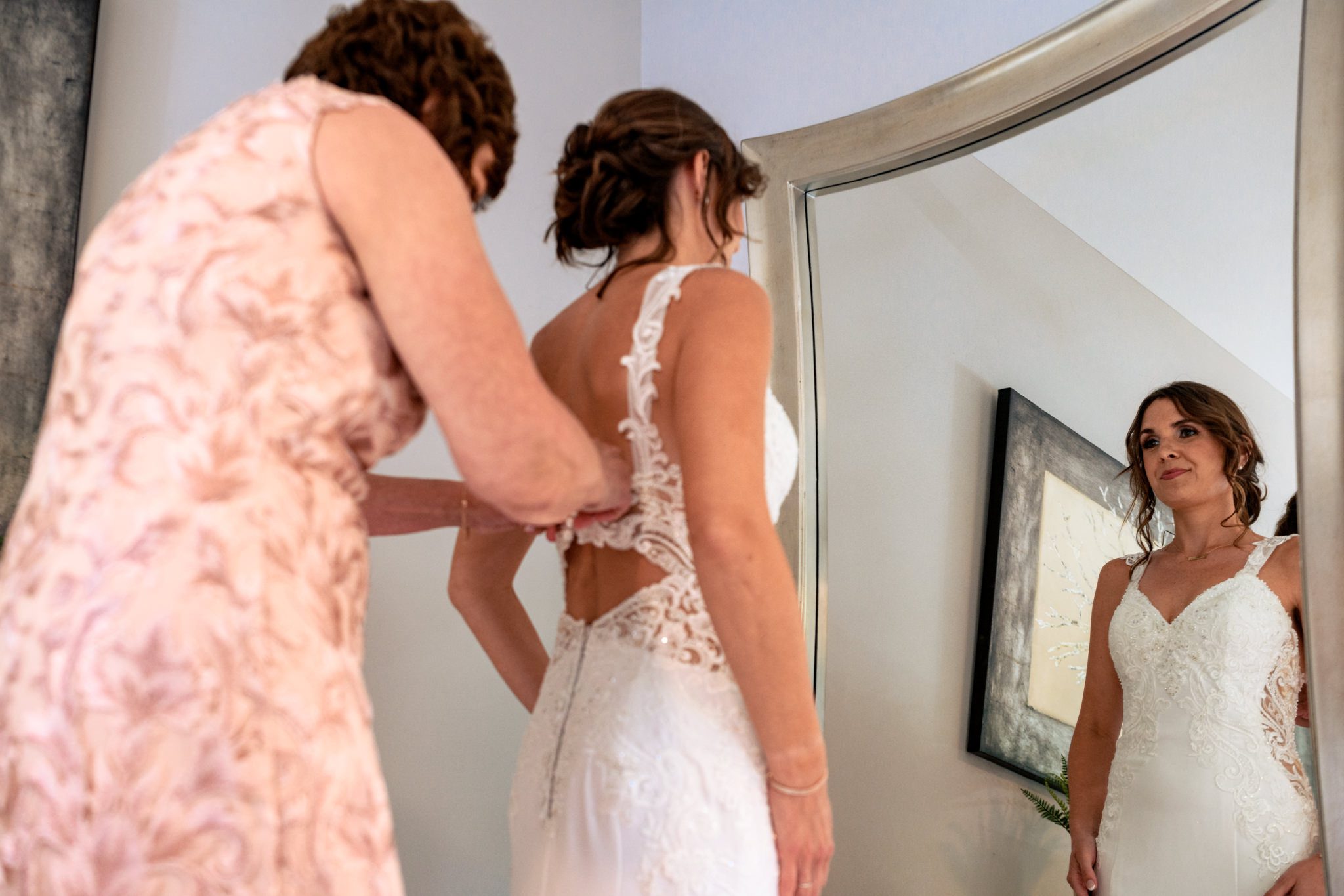A bride getting her wedding dress on in front of a mirror at the Crest Pavilion captured by a documentary wedding photographer.