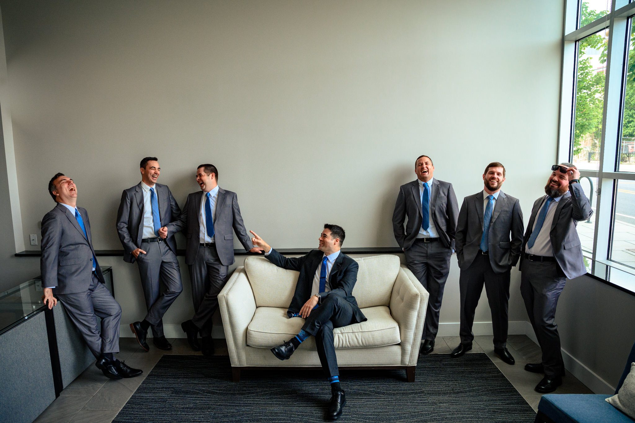 A group of men in suits sitting on a couch at the Crest Pavilion, captured by a documentary wedding photographer.