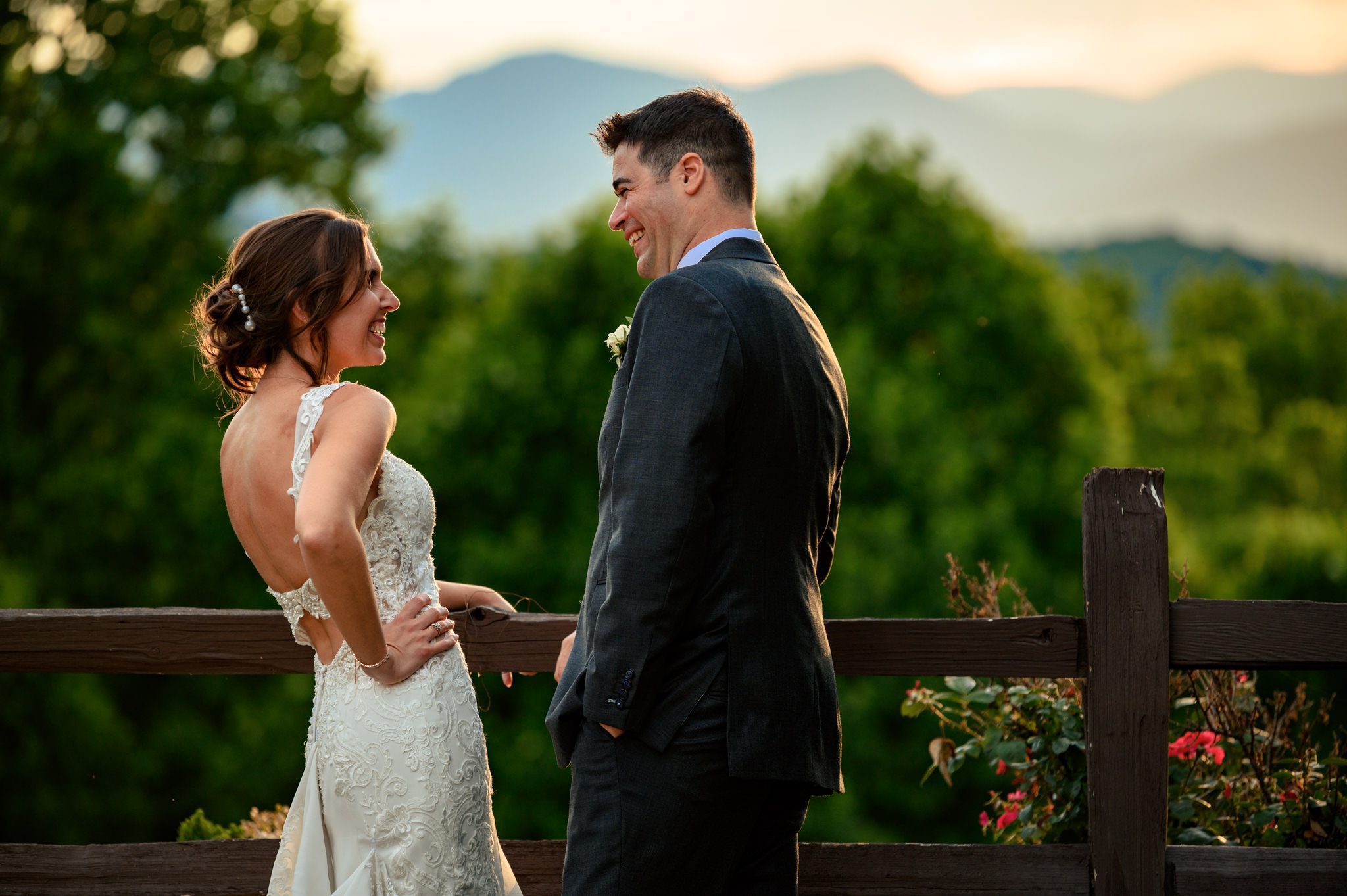 A documentary wedding photographer capturing a bride and groom at the Crest Pavilion, standing on a fence overlooking mountains.