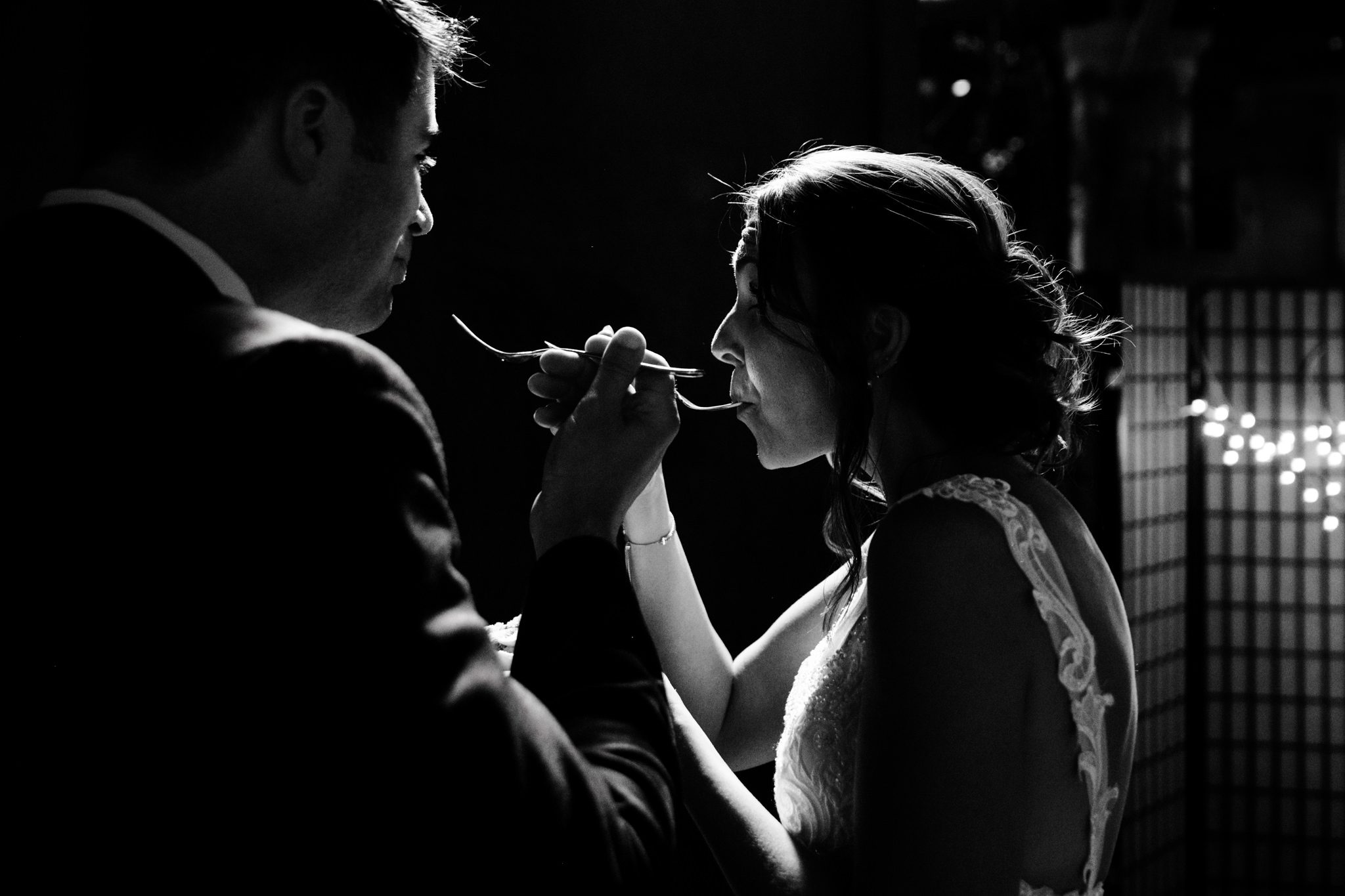 A documentary wedding photographer captures a bride and groom feeding each other at Crest Pavilion.