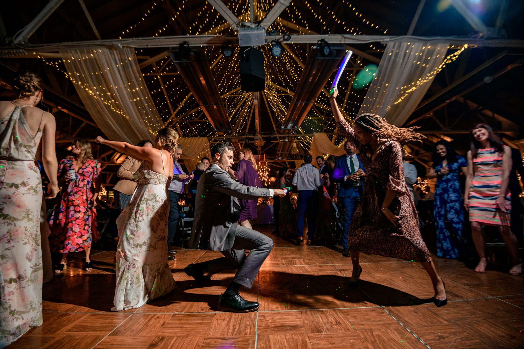 A documentary wedding photographer captures a group of people dancing at a wedding reception held at the Crest Pavilion.