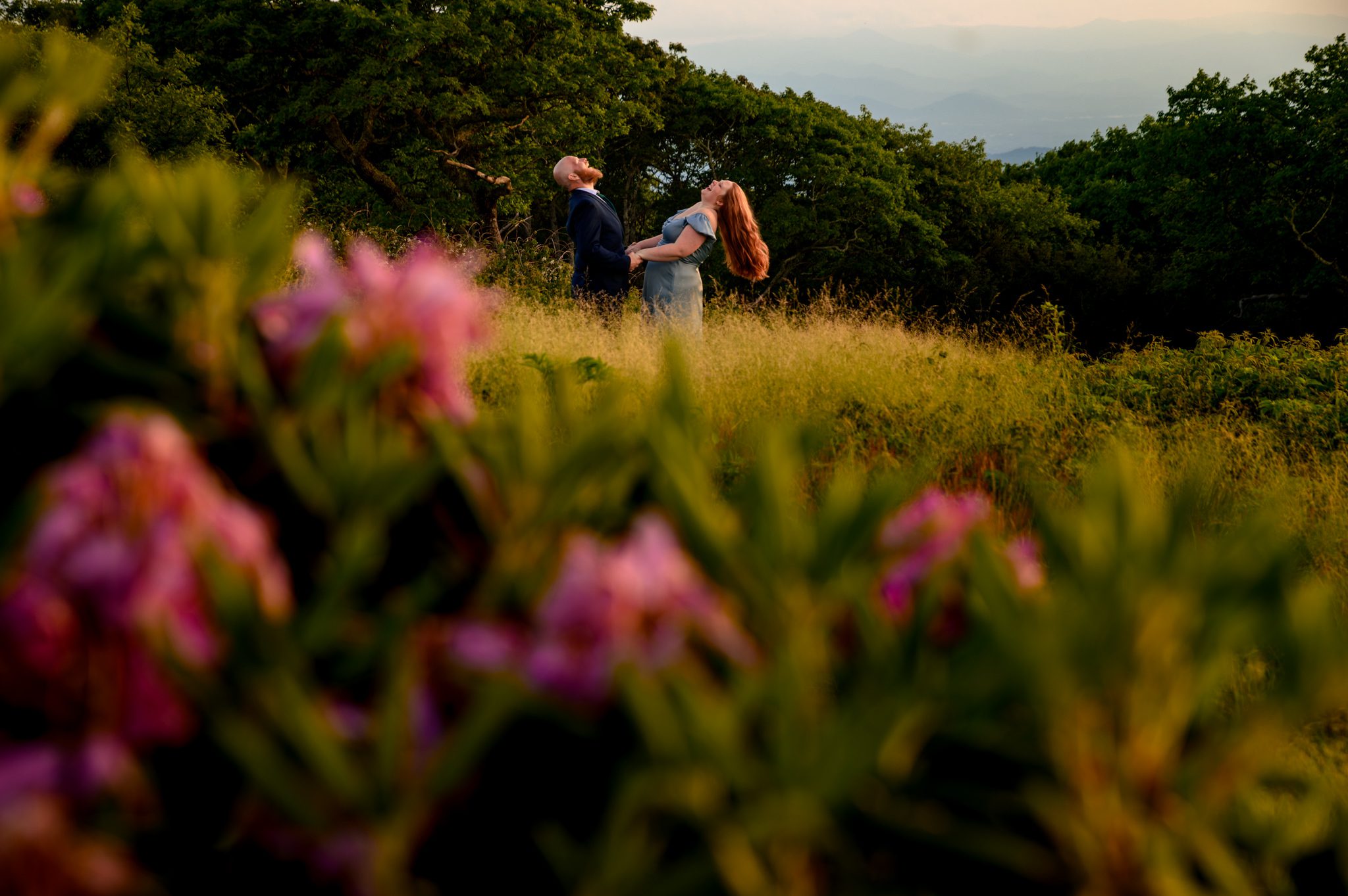 engaged couple standing in purple summer rhododendron thicket blooms at craggy gardens on the blue ridge parkway