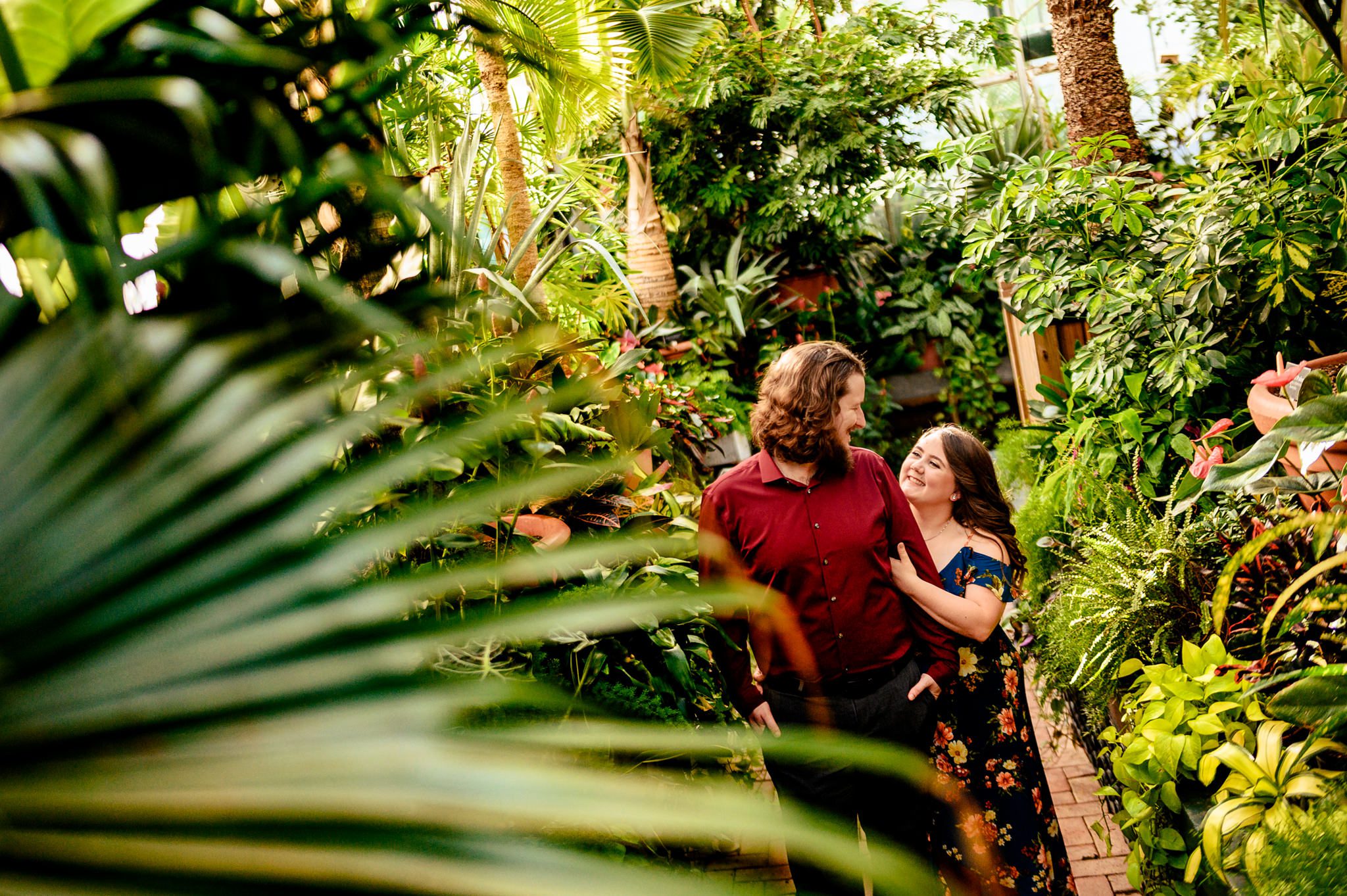 engaged couple laughing inside biltmore conservatory with tropical plants around them