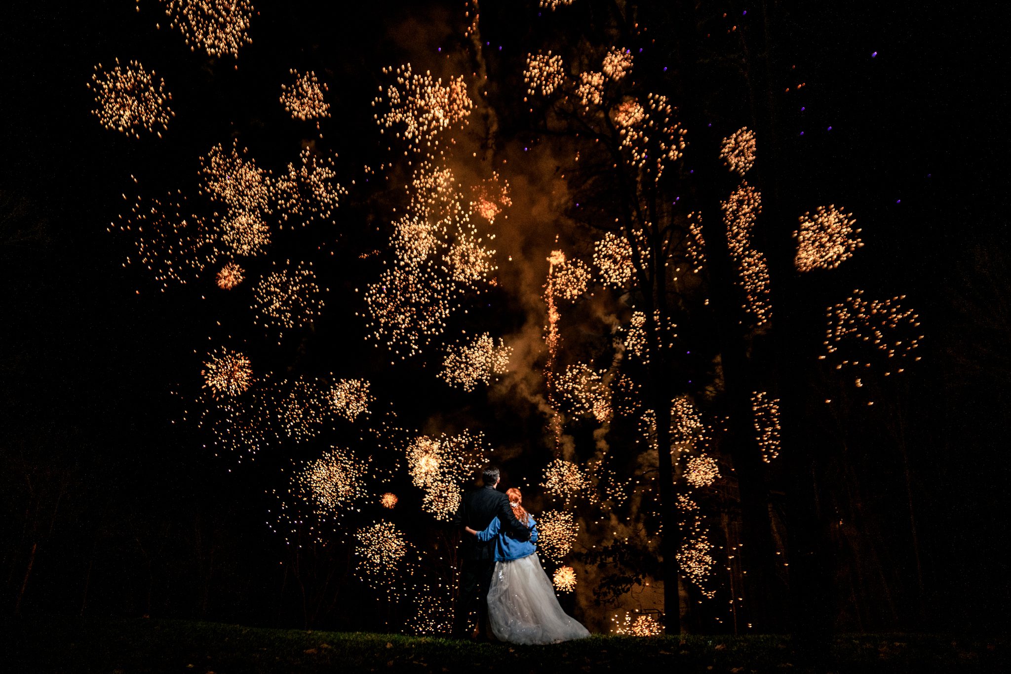 A bride and groom captured by an Asheville wedding photographer, standing in front of a mesmerizing firework display.