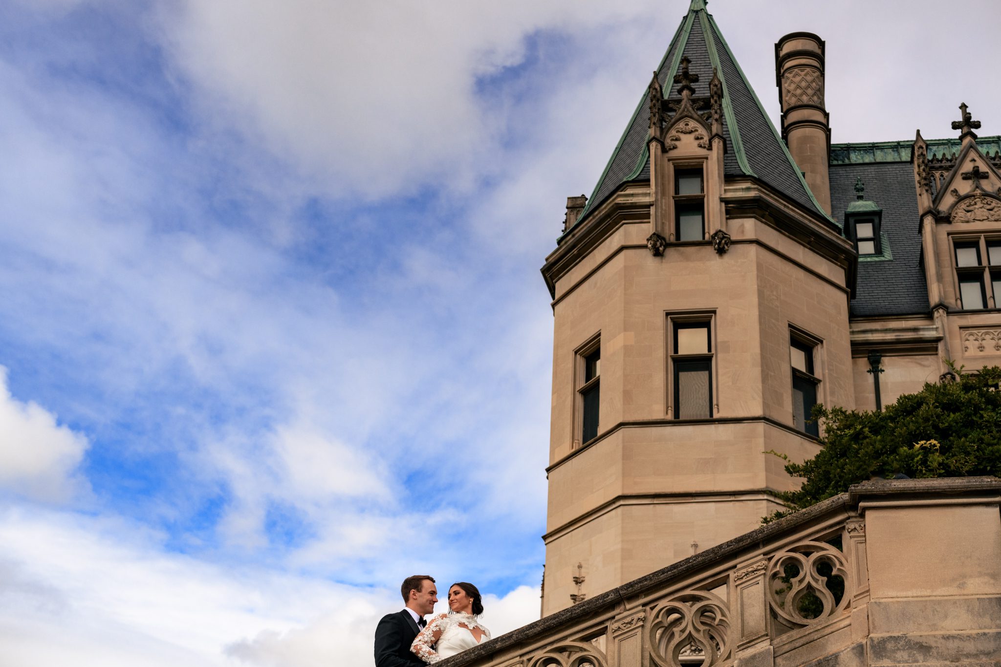 Bride and groom in elegant attire, standing on South Terrace steps at Biltmore Estate, surrounded by lush scenery
