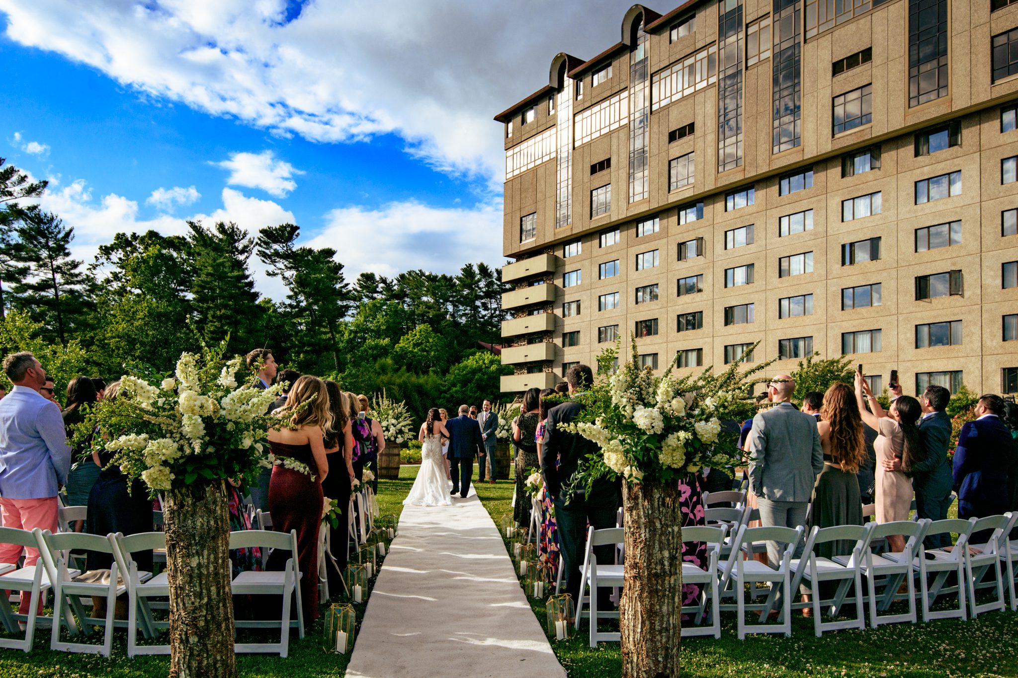 father walks his daughter the bride down the aisle of a grove park inn wedding at the seely pavilion lawn