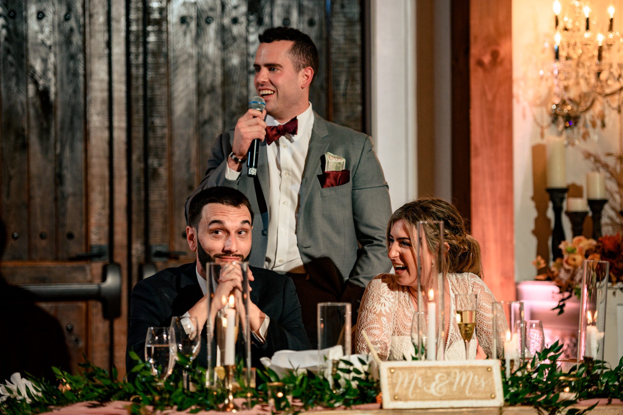 Bride and groom laugh heavily during the toast portion of their wedding reception