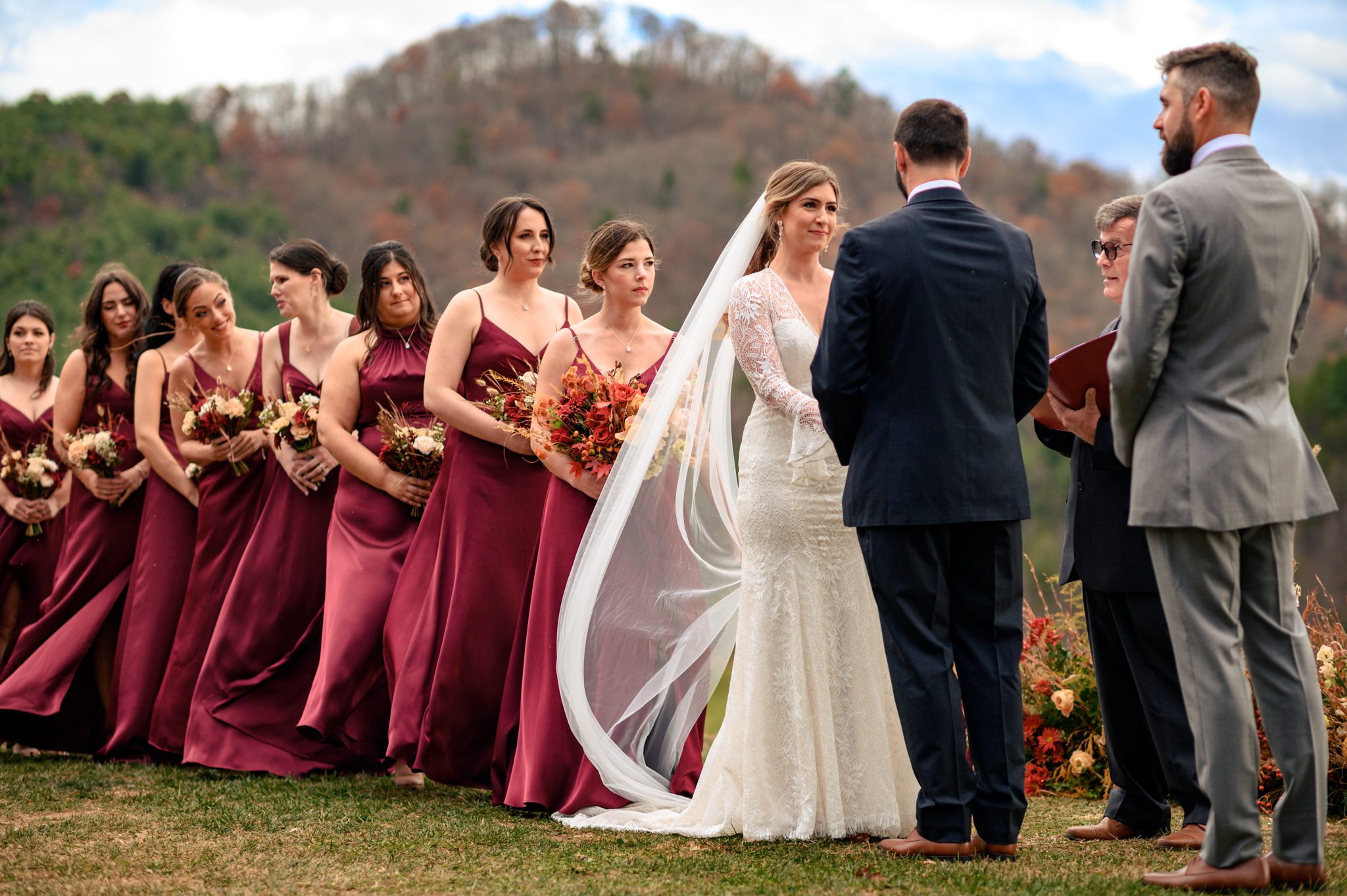 A wedding ceremony at The Ridge Asheville wedding venue with bridesmaids in burgundy dresses.