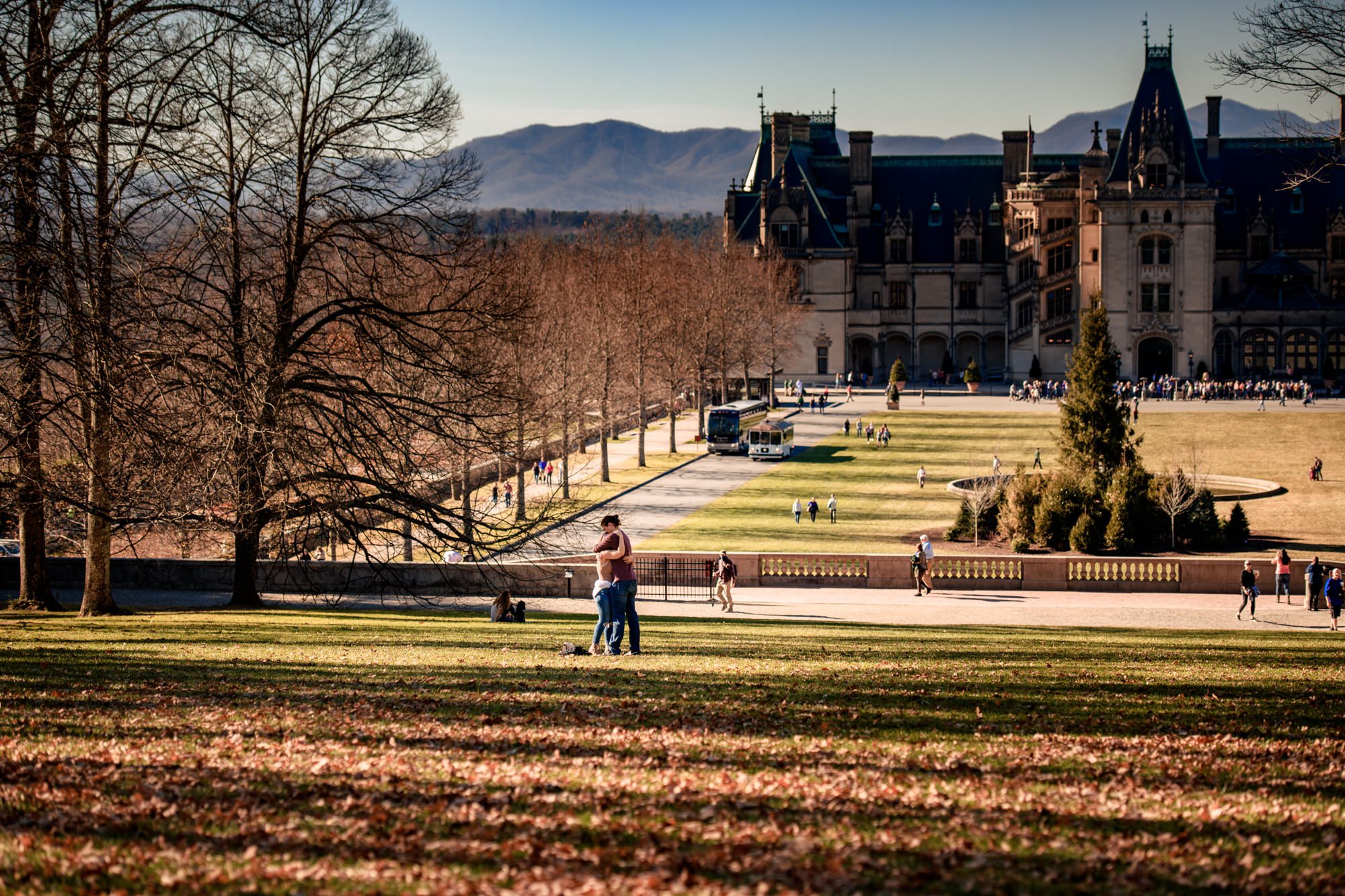 The couple sharing a tender kiss post-proposal, with the historic Biltmore mansion looming majestically in the background