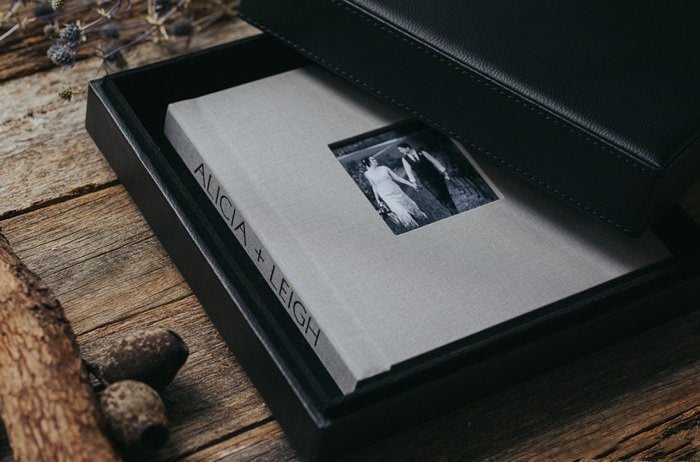 A wedding photo album in a box on a wooden table.