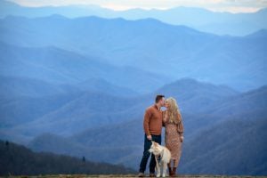 married couple kissing with layered mountains behind them on the blue ridge parkway
