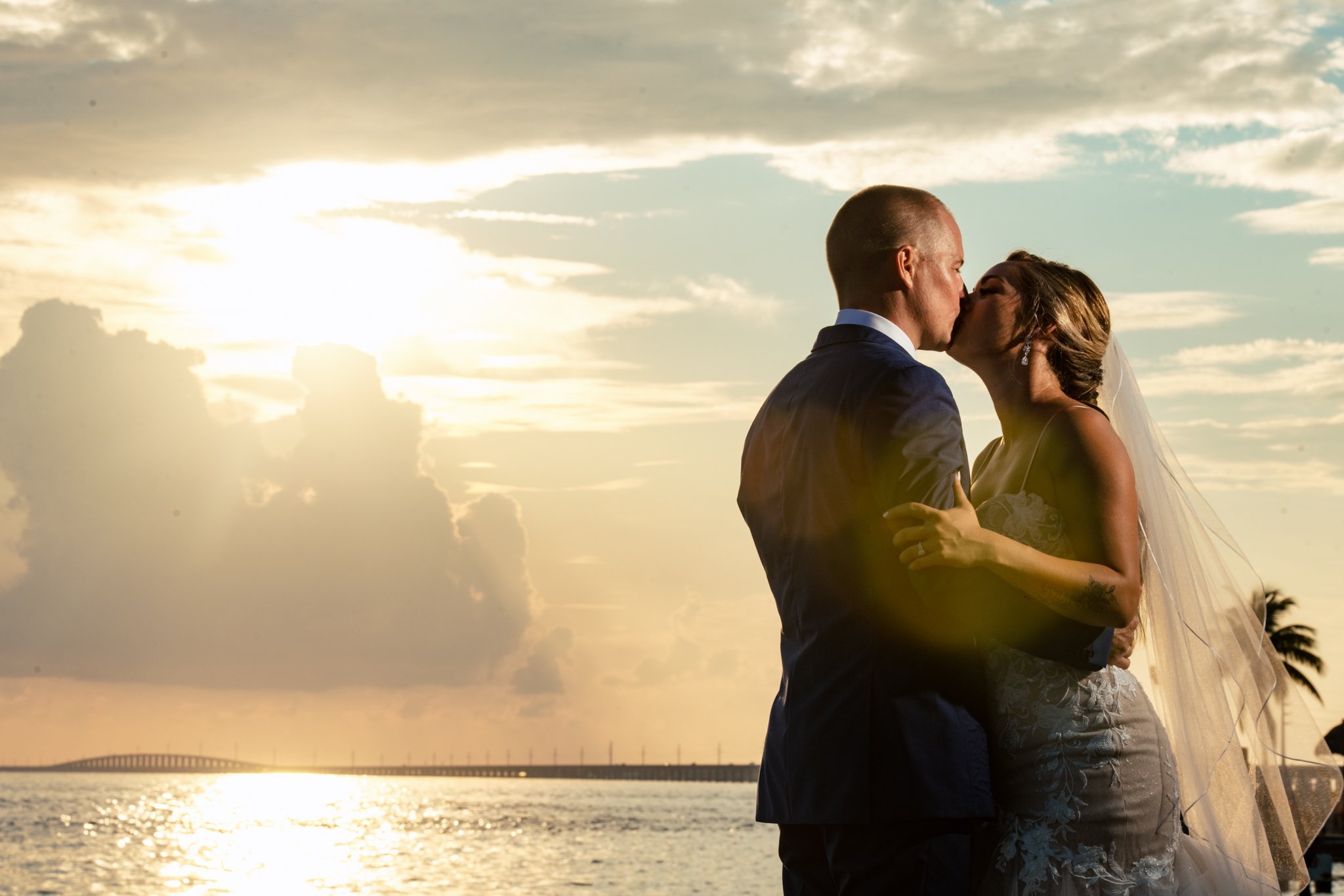 Newlyweds embracing against the backdrop of Isla Bella Beach Resort's sunset view