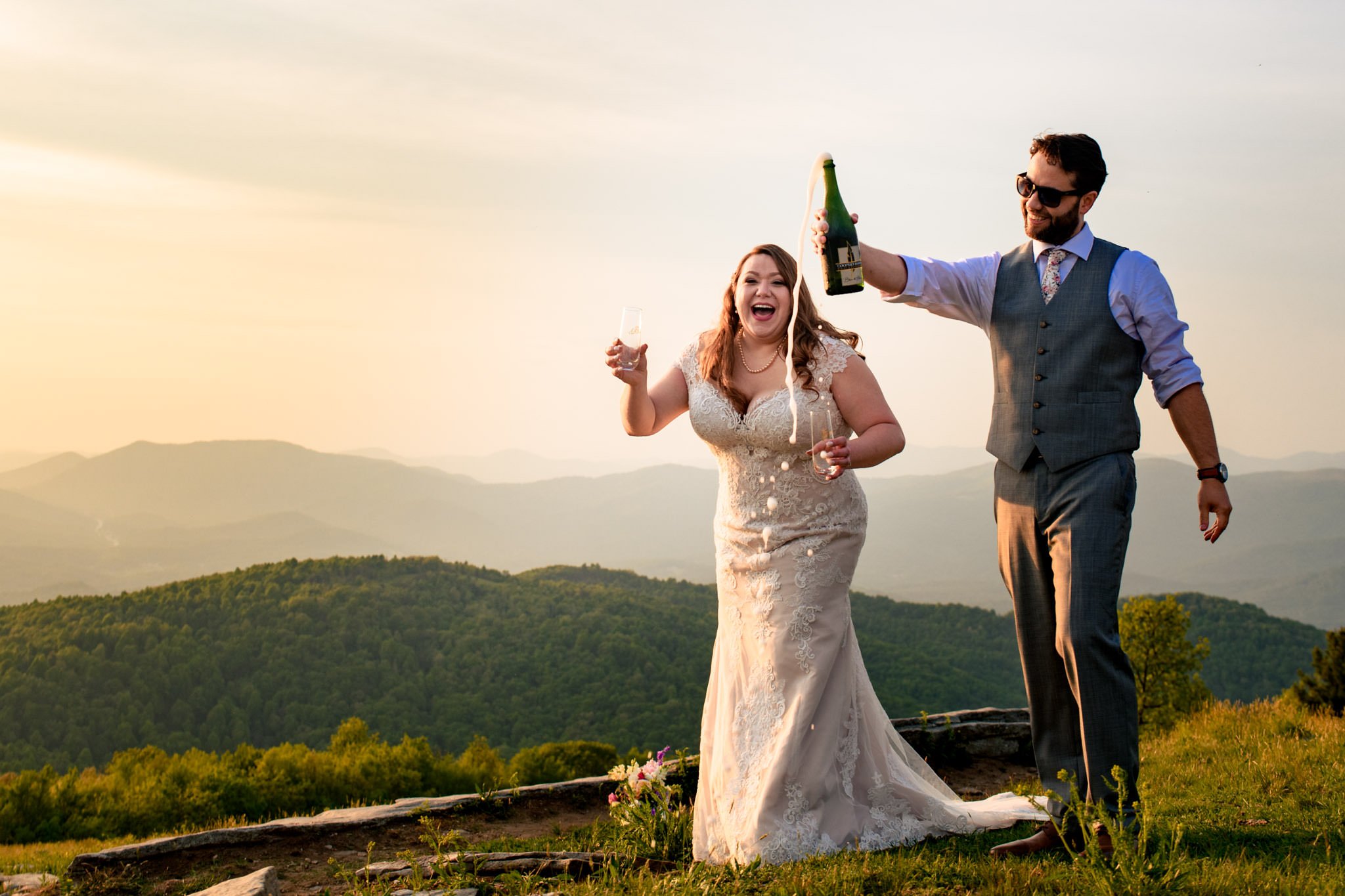 Asheville wedding photographer captures couple toasting champagne on mountaintop.