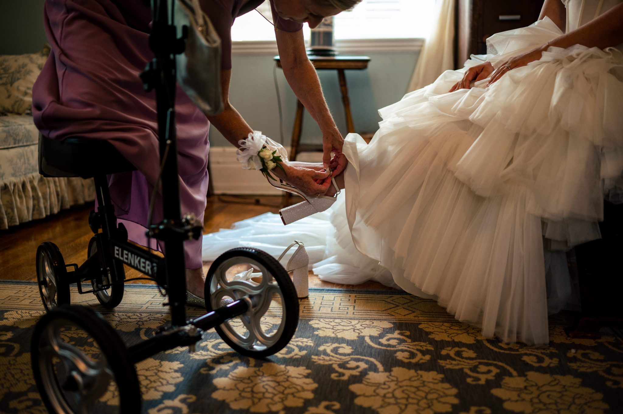 A woman putting on a bride's dress on a wheel chair.