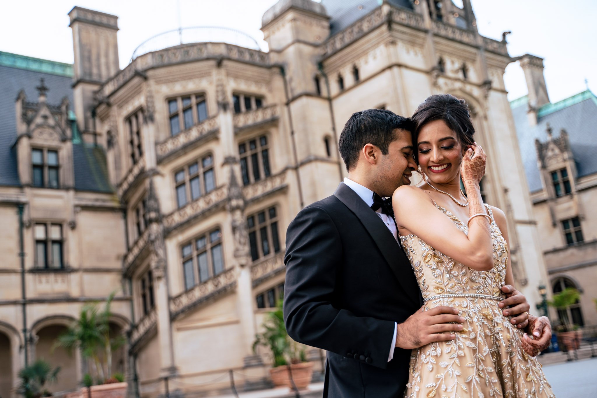 A bride and groom embracing in front of the Biltmore Estate.